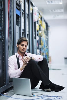 businessman with laptop in network server room photo