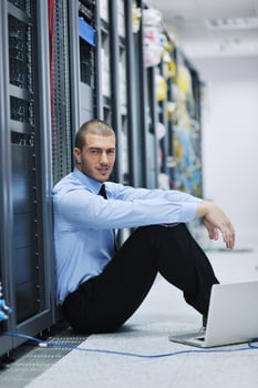 businessman with laptop in network server room photo