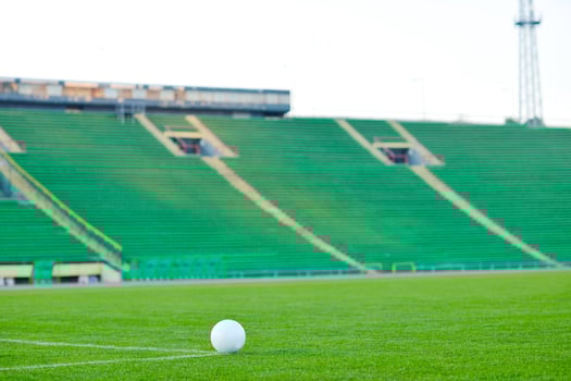 Soccer ball on grass at goal and stadium in background photo