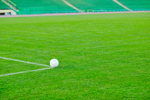 Soccer ball on grass at goal and stadium in background photo