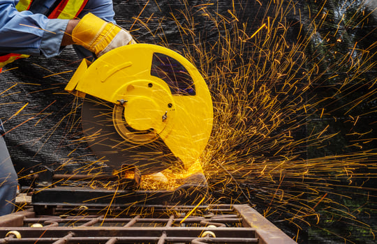 Industrial technician engineer in blue protective cloth wear safety mask, Man working with electric grinder tool on steel structure with   sparks flying in factory, selective focus photo