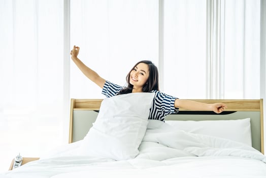 Beautiful young woman stretching in bed with her arms raised after wake up,  Healthy lifestyle, Wellness concept photo