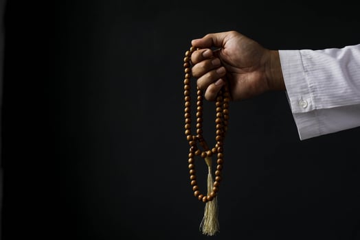 Muslim man hand holding prayer beads isolated on black background with copy space photo