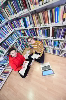 the students uses a notebook, laptop and a school library photo
