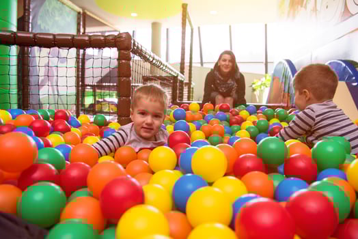 young mom playing with kids in pool with colorful balls photo