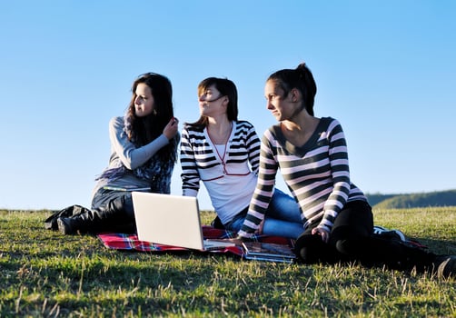 group of teens working on laptop outdoor photo