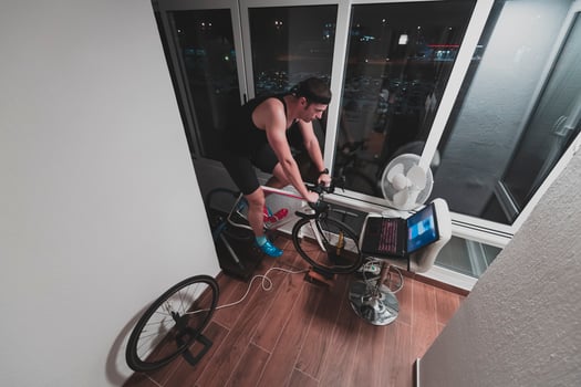 Man cycling on the machine trainer he is exercising in the home at night playing online bike racing game photo