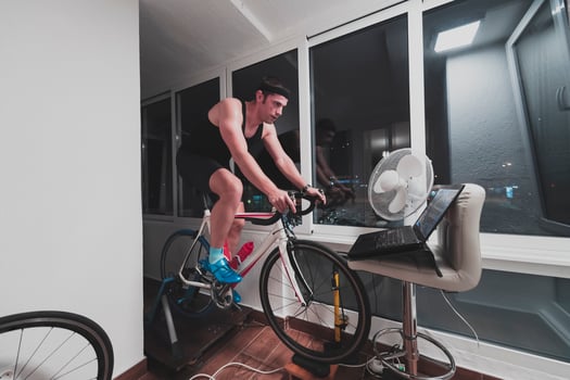 Man cycling on the machine trainer he is exercising in the home at night playing online bike racing game photo
