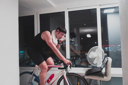 Man cycling on the machine trainer he is exercising in the home at night playing online bike racing game photo