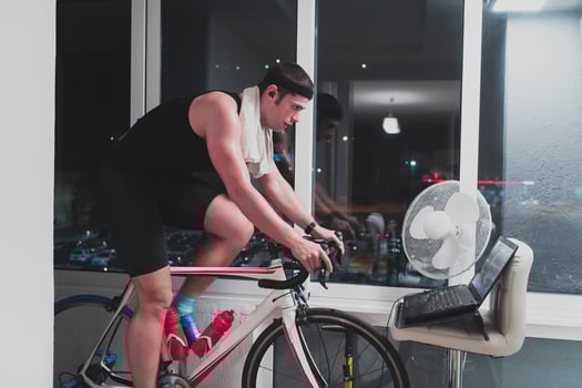 Man cycling on the machine trainer he is exercising in the home at night playing online bike racing game photo