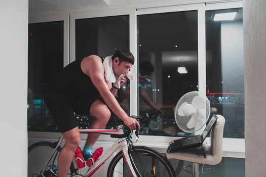 Man cycling on the machine trainer he is exercising in the home at night playing online bike racing game photo