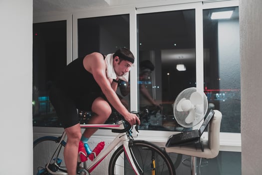 Man cycling on the machine trainer he is exercising in the home at night playing online bike racing game photo