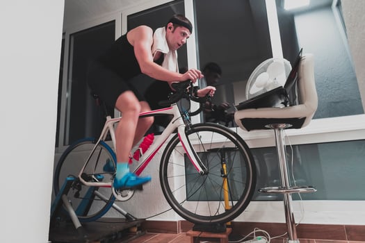 Man cycling on the machine trainer he is exercising in the home at night playing online bike racing game photo