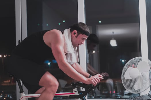 Man cycling on the machine trainer he is exercising in the home at night playing online bike racing game photo