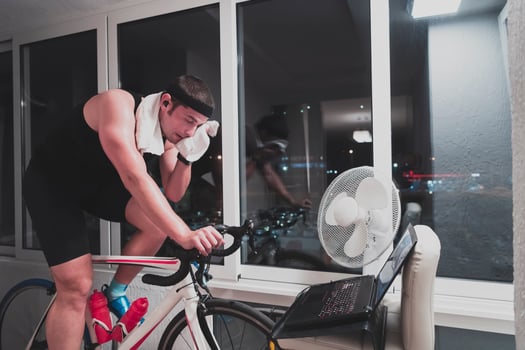 Man cycling on the machine trainer he is exercising in the home at night playing online bike racing game photo