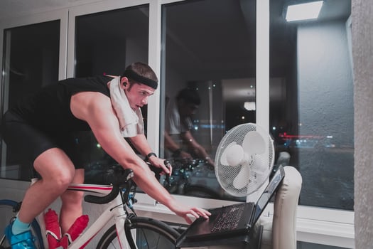 Man cycling on the machine trainer he is exercising in the home at night playing online bike racing game photo
