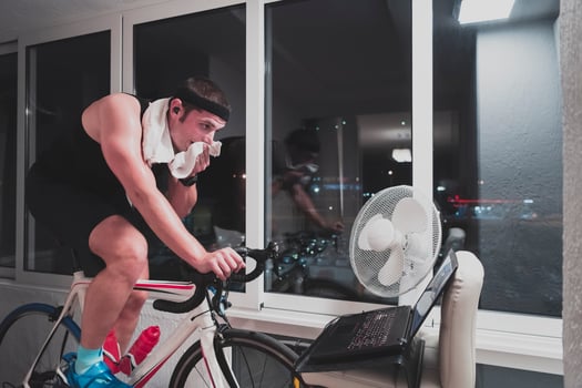 Man cycling on the machine trainer he is exercising in the home at night playing online bike racing game photo