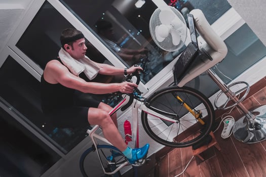 Man cycling on the machine trainer he is exercising in the home at night playing online bike racing game photo