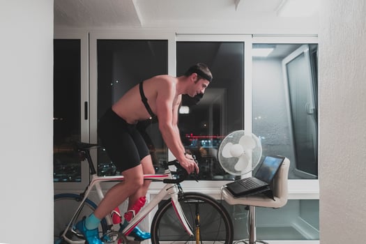 Man cycling on the machine trainer he is exercising in the home at night playing online bike racing game photo