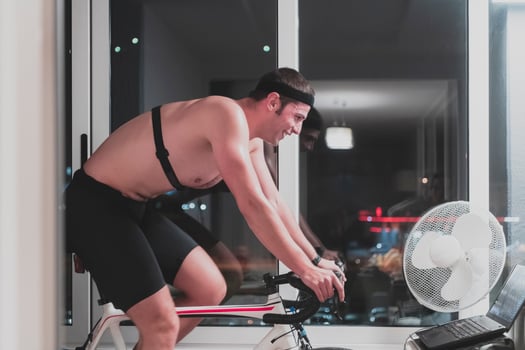 Man cycling on the machine trainer he is exercising in the home at night playing online bike racing game photo