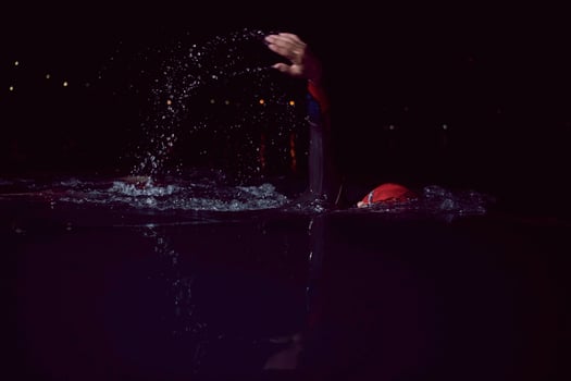 triathlon athlete swimming in dark night  wearing wetsuit photo