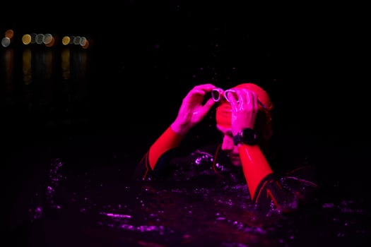 authentic triathlete swimmer having a break during hard training on night neon gel light photo