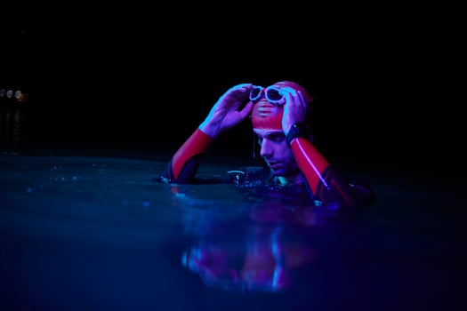 authentic triathlete swimmer having a break during hard training on night neon gel light photo