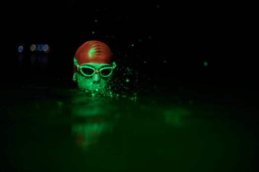 authentic triathlete swimmer having a break during hard training on night neon gel light photo