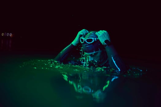 authentic triathlete swimmer having a break during hard training on night neon gel light photo