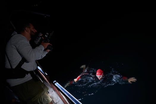 videographer  taking action shot of triathlon swimming athlete at night photo