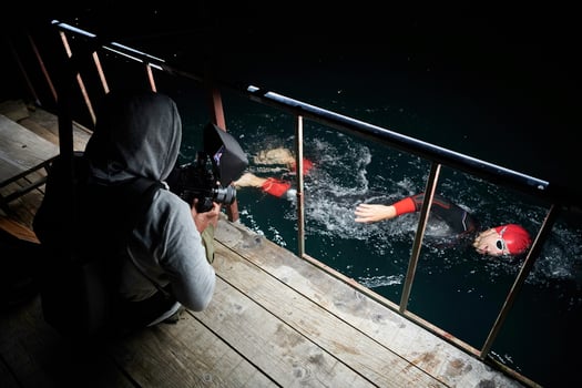 videographer  taking action shot of triathlon swimming athlete at night photo