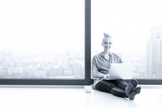 woman drinking coffee and using laptop at home photo