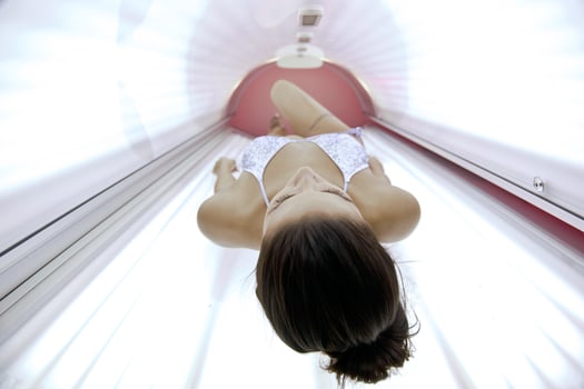Beautiful young woman tanning in solarium photo