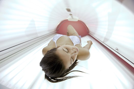 Beautiful young woman tanning in solarium photo