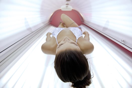 Beautiful young woman tanning in solarium photo