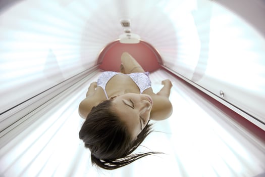 Beautiful young woman tanning in solarium photo