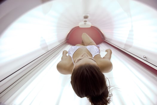Beautiful young woman tanning in solarium photo