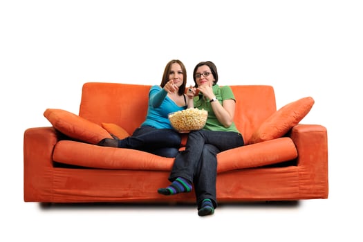 female friends eating popcorn and watching tv at home photo