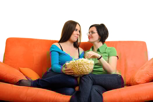 female friends eating popcorn and watching tv at home photo