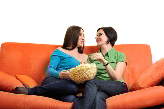 female friends eating popcorn and watching tv at home photo