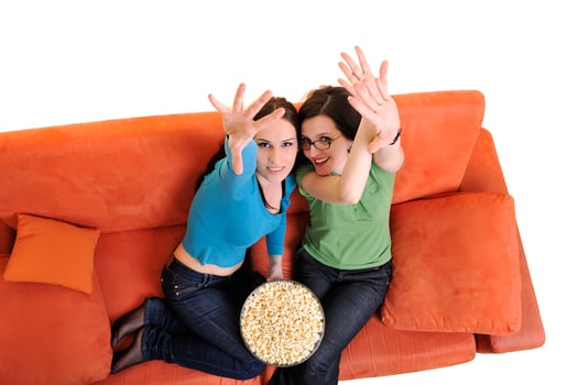female friends eating popcorn and watching tv at home photo