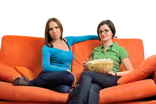female friends eating popcorn and watching tv at home photo