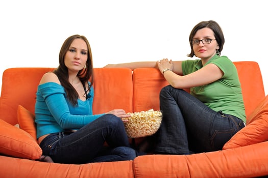 female friends eating popcorn and watching tv at home photo