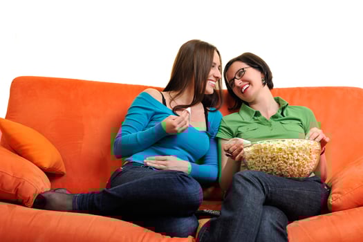 female friends eating popcorn and watching tv at home photo