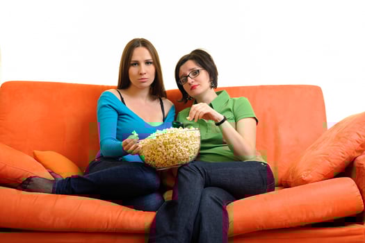 female friends eating popcorn and watching tv at home photo