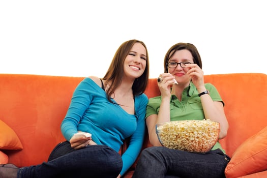 female friends eating popcorn and watching tv at home photo