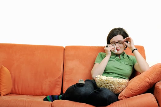 young woman eat popcorn on orange sofa photo