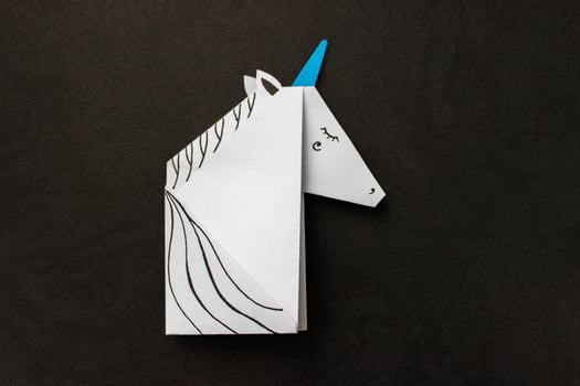 White unicorn made in the origami technique on black background. With place for your text. photo