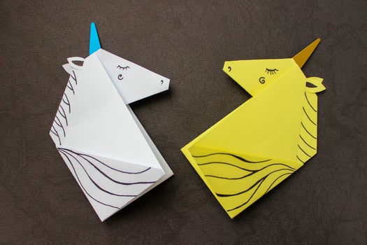 White and yellow unicorns made in the origami technique on black background. photo