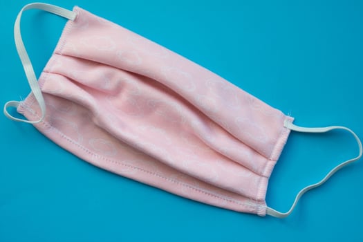Reusable medical mask sewn from fabric. Pink medical mask on a blue background. Virus and bacteria protection photo
